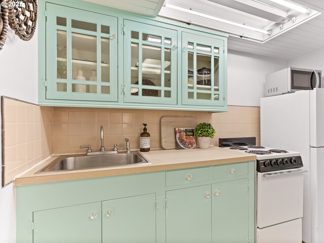 kitchen featuring a sink, green cabinetry, decorative backsplash, and white range with electric cooktop