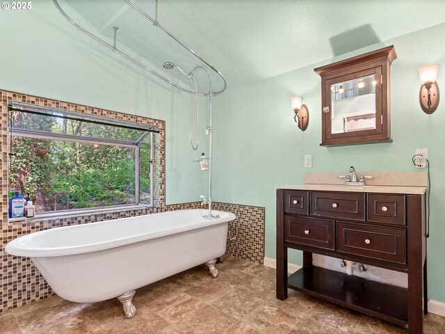 bathroom featuring vanity, tile patterned floors, baseboards, tile walls, and a soaking tub