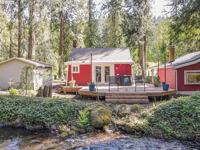 rear view of property featuring french doors, a deck, a chimney, and a shingled roof