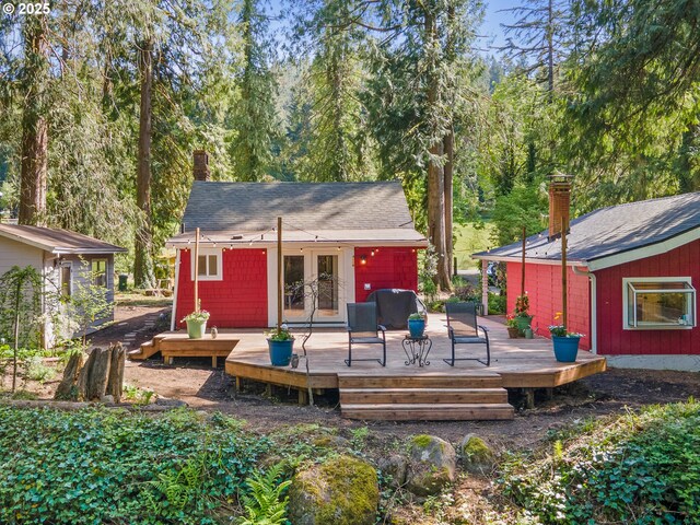 rear view of property featuring french doors, a wooden deck, a chimney, and a shingled roof