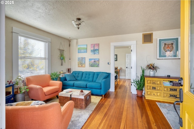 living area featuring visible vents, a textured ceiling, and hardwood / wood-style flooring