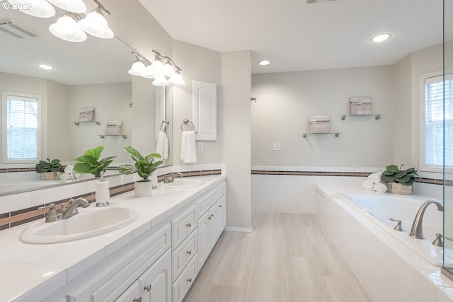 full bath with a bath, visible vents, double vanity, and a sink