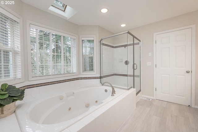 bathroom featuring a shower stall, a jetted tub, baseboards, recessed lighting, and a skylight