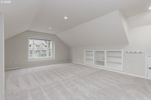 additional living space featuring lofted ceiling, built in shelves, baseboards, and carpet floors