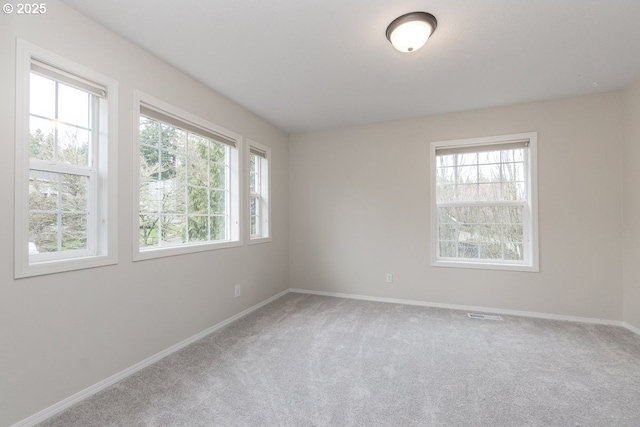 unfurnished room with baseboards, carpet floors, and visible vents