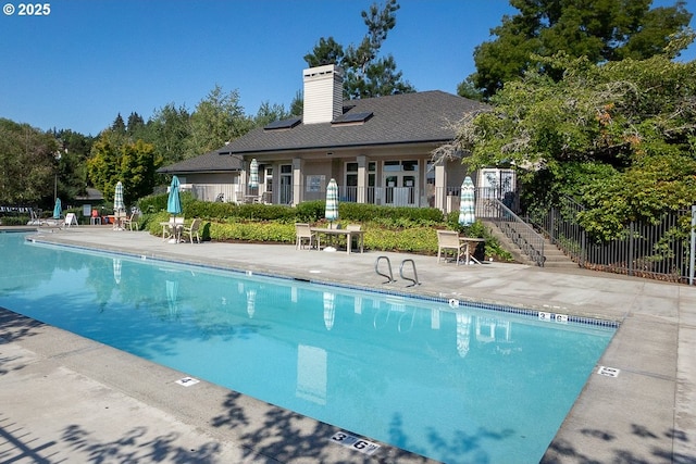 community pool featuring stairway, a patio, and fence