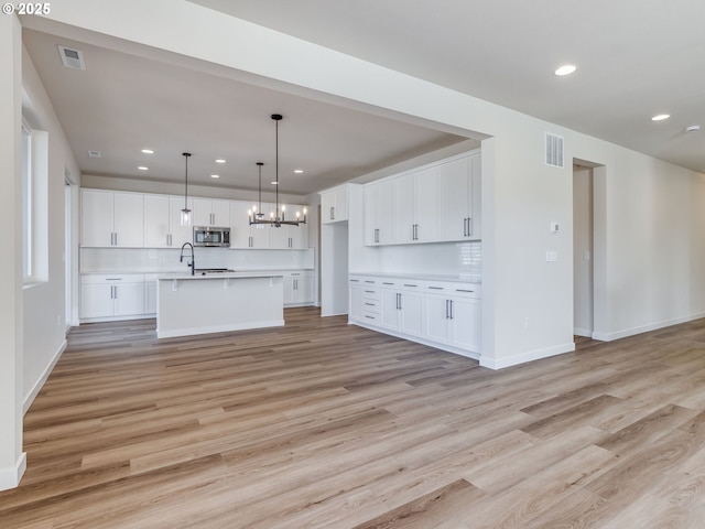 kitchen with visible vents, light countertops, light wood finished floors, and stainless steel microwave