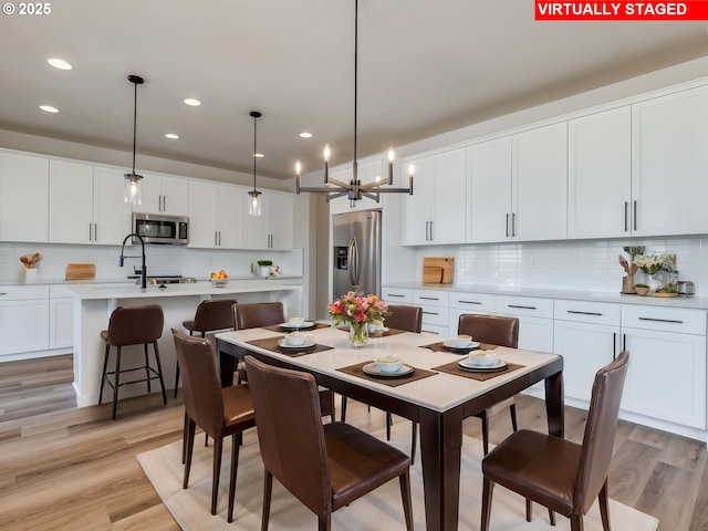 dining room with recessed lighting, an inviting chandelier, and light wood finished floors