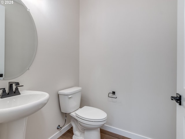 bathroom featuring a sink, baseboards, toilet, and wood finished floors