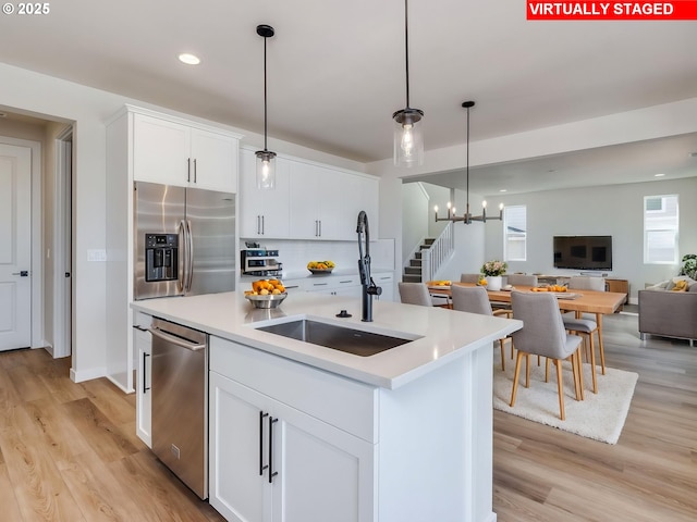 kitchen featuring a sink, appliances with stainless steel finishes, light wood-type flooring, and open floor plan