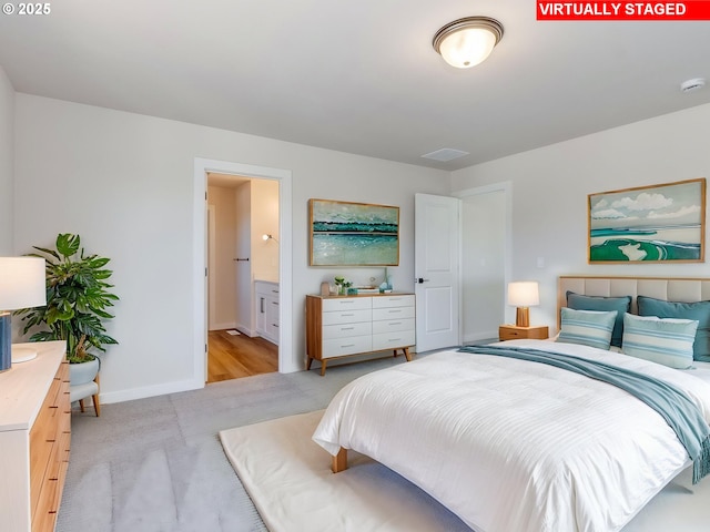 bedroom featuring baseboards, ensuite bathroom, and light carpet