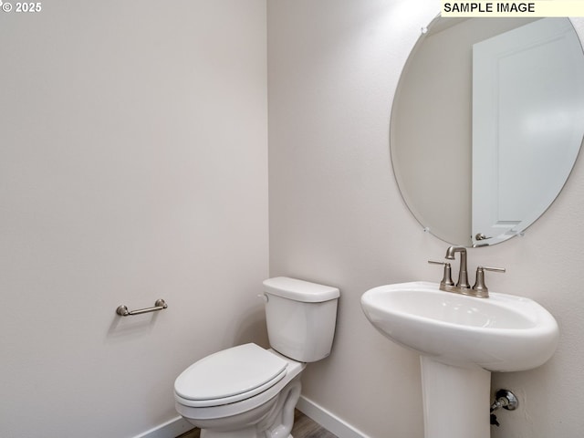 bathroom with hardwood / wood-style flooring, toilet, and sink