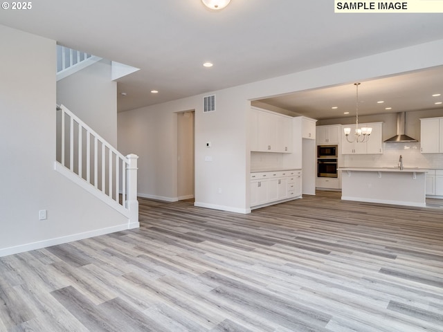 unfurnished living room with a chandelier, light hardwood / wood-style floors, and sink