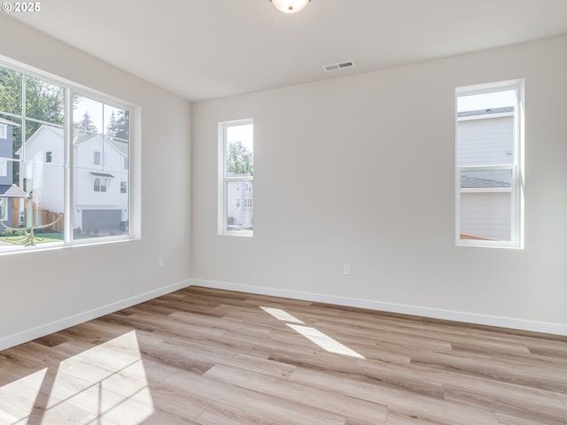 spare room with visible vents, light wood-style floors, baseboards, and a healthy amount of sunlight