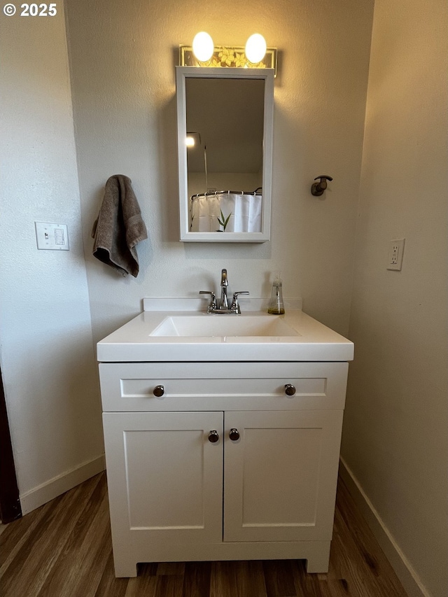 full bathroom with wood finished floors, vanity, and baseboards