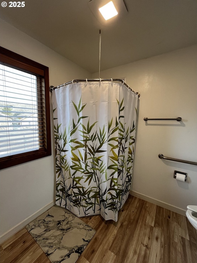 bathroom featuring curtained shower, baseboards, and wood finished floors