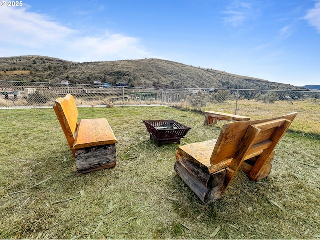 view of yard with a rural view, a mountain view, a fire pit, and fence