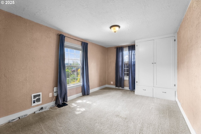 interior space featuring baseboards, a textured wall, carpet flooring, and a textured ceiling