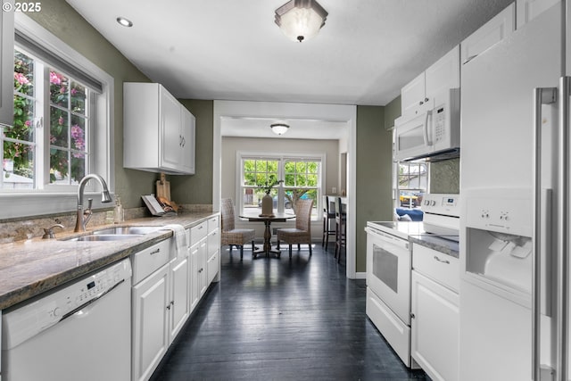 kitchen featuring dark wood-type flooring, a sink, white cabinets, and white appliances