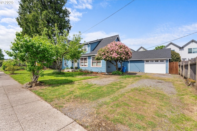 view of front of property with fence, roof with shingles, an attached garage, a front yard, and driveway