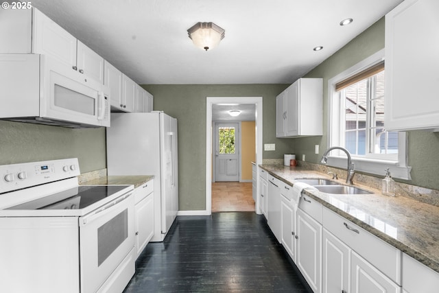 kitchen with white appliances, baseboards, a sink, and white cabinets