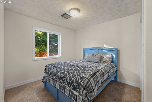 bedroom with carpet floors and a textured ceiling