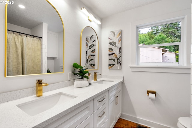 7170 SW 76th Ave, Portland, OR 97223 - bathroom with double vanity, a textured ceiling, and wood finished floors