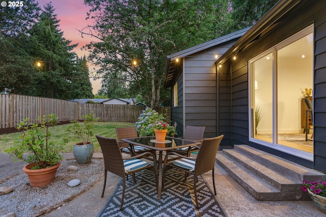 7170 SW 76th Ave, Portland, OR 97223 - patio terrace at dusk featuring a patio, a fenced backyard, outdoor dining space, and entry steps