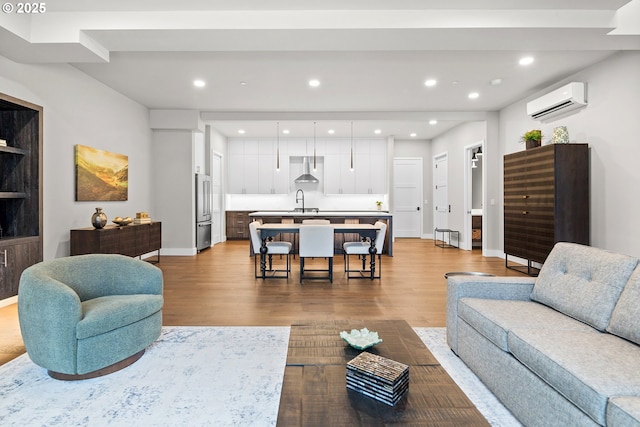 living area featuring baseboards, a wall mounted AC, recessed lighting, and light wood-style floors