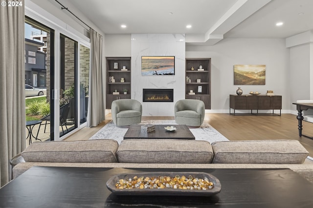 living room with baseboards, a premium fireplace, recessed lighting, and light wood-style floors