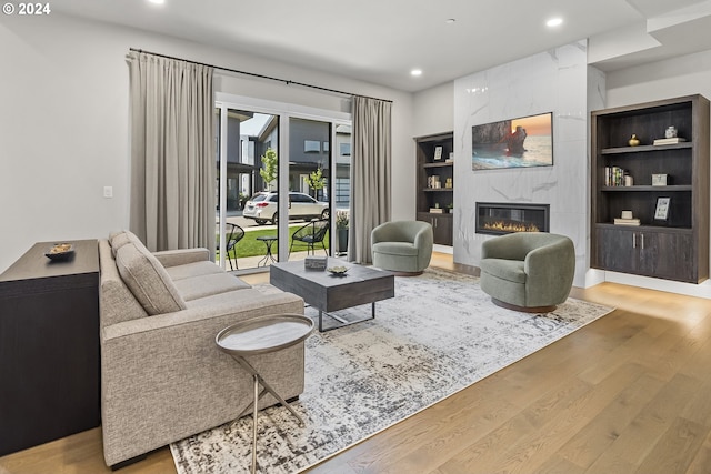 living area with built in shelves, light wood-type flooring, a fireplace, and recessed lighting