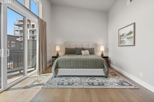 bedroom with access to exterior, visible vents, baseboards, and wood finished floors