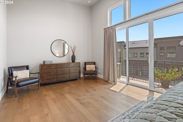 sitting room with a towering ceiling, light wood-style flooring, and baseboards