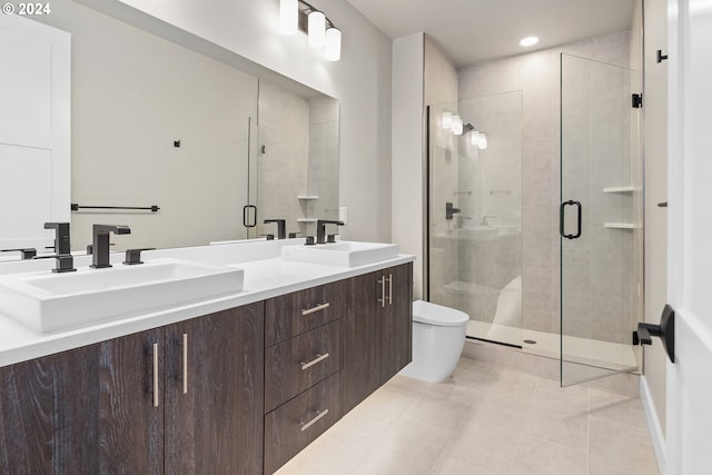 bathroom featuring toilet, a stall shower, double vanity, and a sink