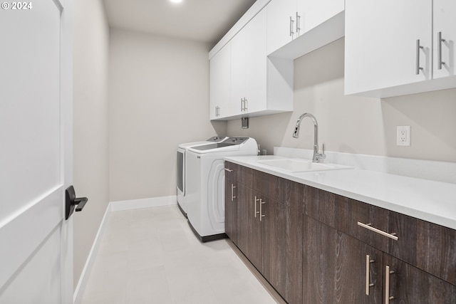 washroom with cabinet space, baseboards, a sink, and independent washer and dryer