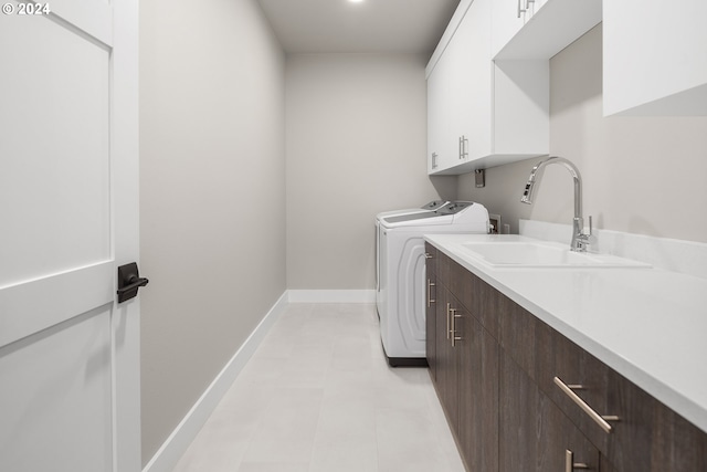 laundry room featuring cabinet space, baseboards, washer and clothes dryer, and a sink