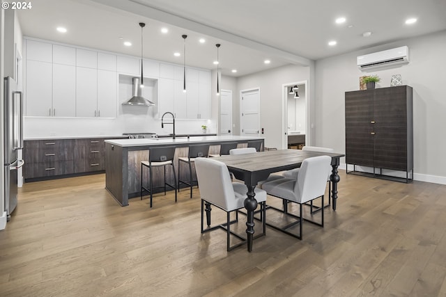 dining room featuring baseboards, a wall mounted air conditioner, light wood-style flooring, and recessed lighting