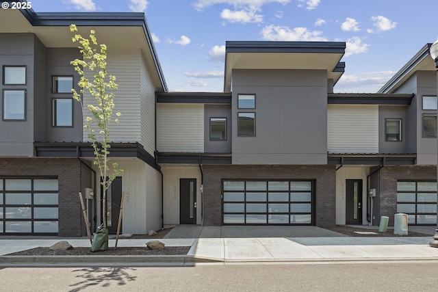 view of front facade with an attached garage, concrete driveway, and brick siding