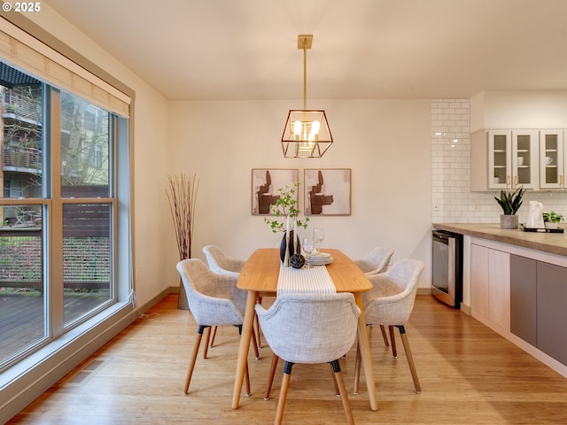 dining area featuring light wood-type flooring, wine cooler, and a wealth of natural light