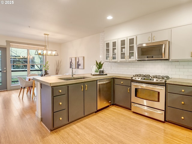 kitchen featuring appliances with stainless steel finishes, hanging light fixtures, gray cabinetry, white cabinets, and sink