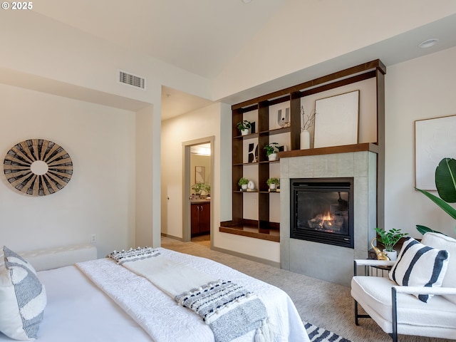 carpeted bedroom featuring vaulted ceiling, a fireplace, and ensuite bath