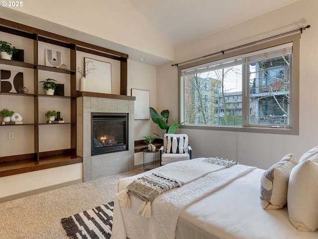 bedroom with lofted ceiling and a tiled fireplace