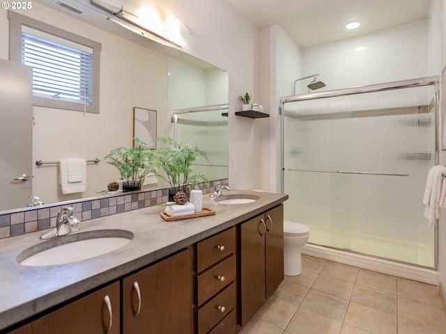 bathroom with toilet, tasteful backsplash, tile patterned flooring, vanity, and a shower with door