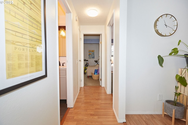 hall featuring light wood-style floors and baseboards