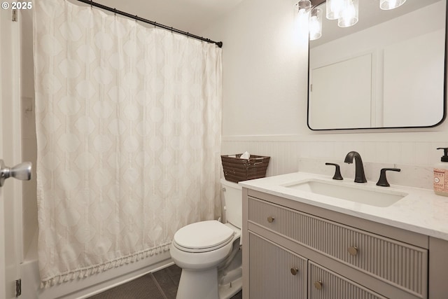 bathroom with vanity, toilet, shower / bathtub combination with curtain, and a wainscoted wall