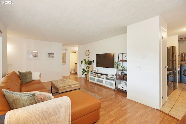 living area with washer / dryer, a textured ceiling, and light wood-style floors