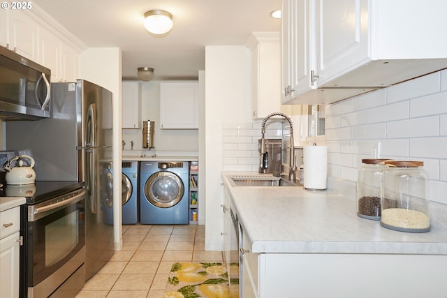 kitchen with washing machine and clothes dryer, light tile patterned flooring, a sink, decorative backsplash, and appliances with stainless steel finishes