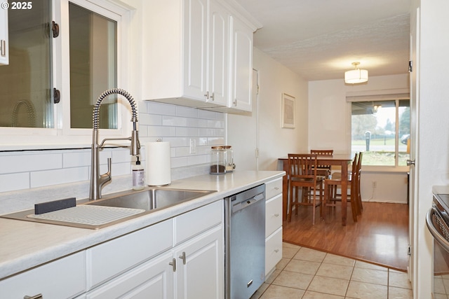 kitchen featuring a sink, stainless steel appliances, white cabinets, light tile patterned floors, and decorative backsplash