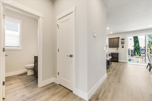 hallway featuring a textured ceiling and light hardwood / wood-style flooring