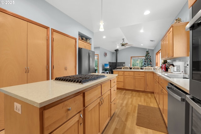 kitchen with lofted ceiling, light hardwood / wood-style flooring, ceiling fan, appliances with stainless steel finishes, and a kitchen island